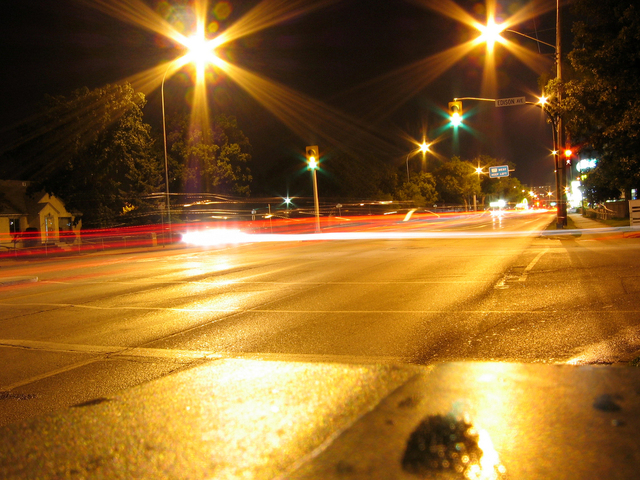 silnice v noci, světla od projíždějících automobilů semafory, na kterých je zelená